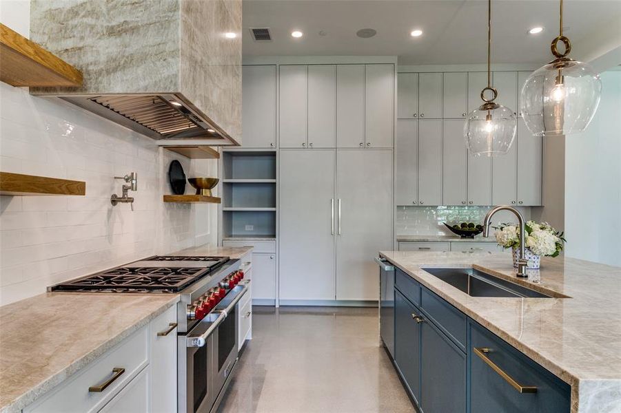 Kitchen featuring backsplash, hanging light fixtures, white cabinets, blue cabinetry, and appliances with stainless steel finishes