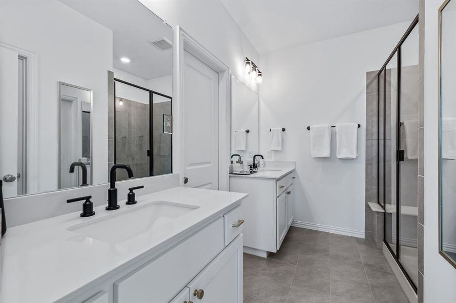 Bathroom featuring tile patterned floors, vanity, and a shower with shower door