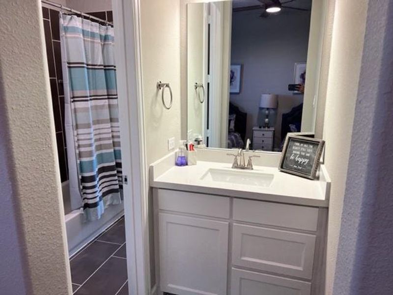 Bathroom with tile floors, shower / bath combination with curtain, and large vanity