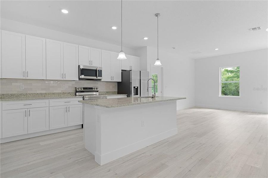 Kitchen with granite countertops, soft-closing cabinets, tiled backsplash, Samsung appliances