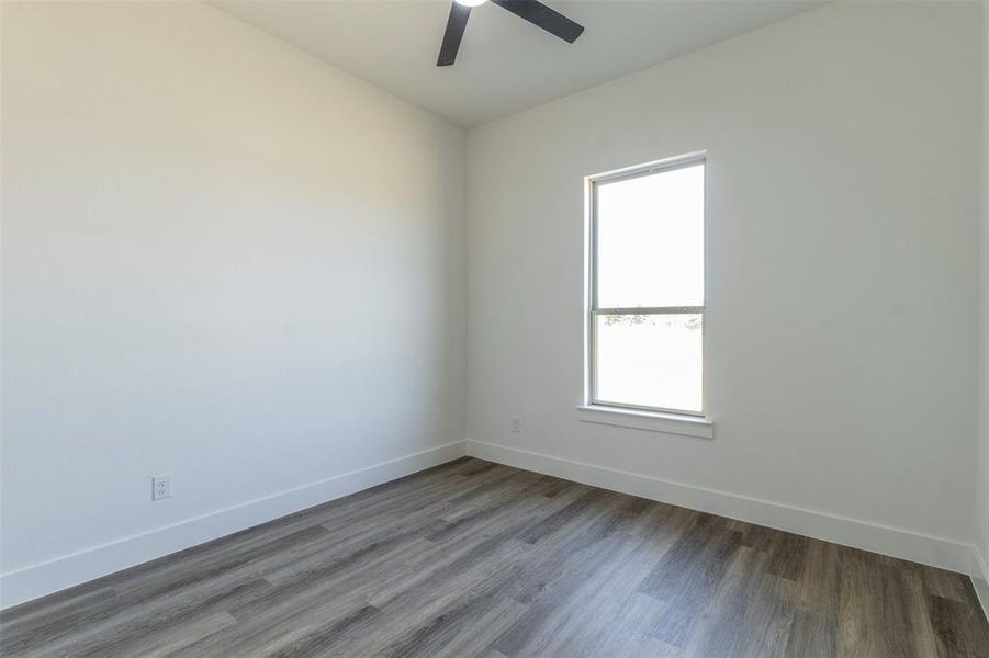 Empty room featuring wood-type flooring, ceiling fan, and a wealth of natural light