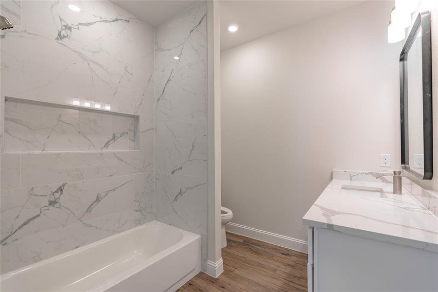 Full bathroom featuring wood-type flooring, toilet, tiled shower / bath, and vanity