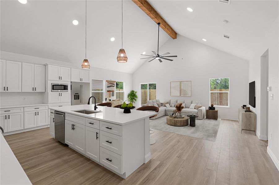 Kitchen with stainless steel appliances, sink, an island with sink, high vaulted ceiling, and white cabinets