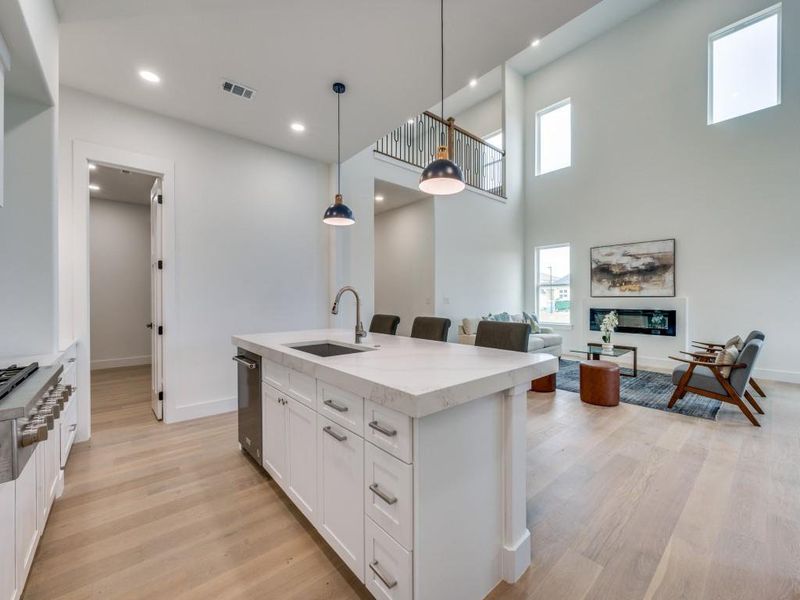 Kitchen with decorative light fixtures, sink, a center island with sink, and plenty of natural light