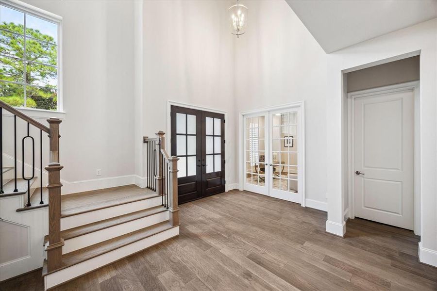 The open layout with rich double doors, warm wood floors, high ceilings and stately iron details creates a grand entrance, setting the stage for the luxury that unfolds throughout this custom built home.