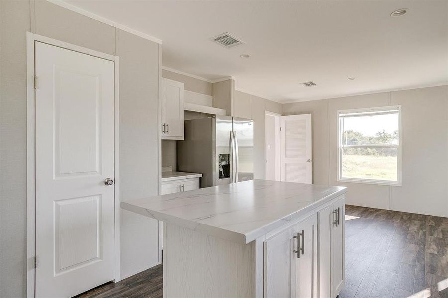 Kitchen with a center island, dark hardwood / wood-style flooring, stainless steel fridge, and white cabinets