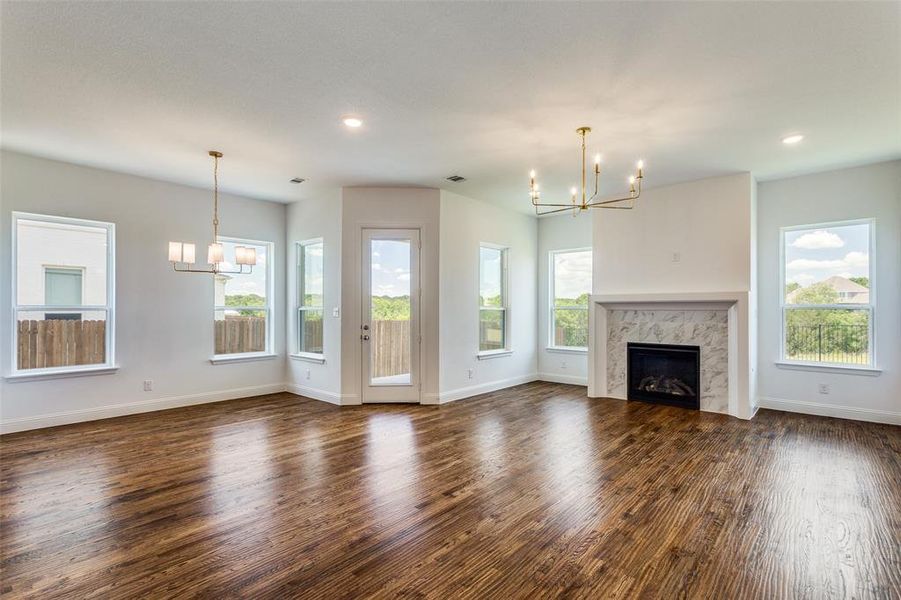 Unfurnished living room with dark hardwood / wood-style flooring, a premium fireplace, and a chandelier