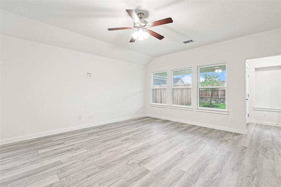 Unfurnished room featuring lofted ceiling, ceiling fan, and light wood-type flooring