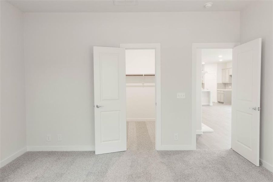 Unfurnished bedroom with light carpet, a walk in closet, and a closet