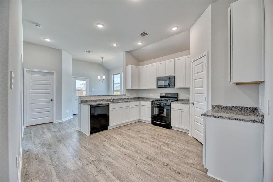 The kitchen showcases elegant granite countertops, enhanced by vinyl plank flooring and classic white cabinets. It includes 42-inch overhead cabinets, providing ample storage space to accommodate all your kitchen essentials.