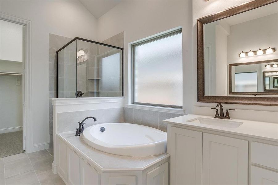 Bathroom with plus walk in shower, vanity, and tile patterned flooring