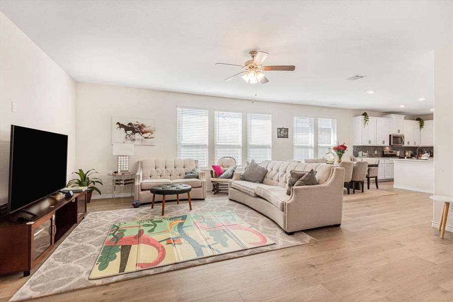 Living room with ceiling fan and light hardwood / wood-style floors