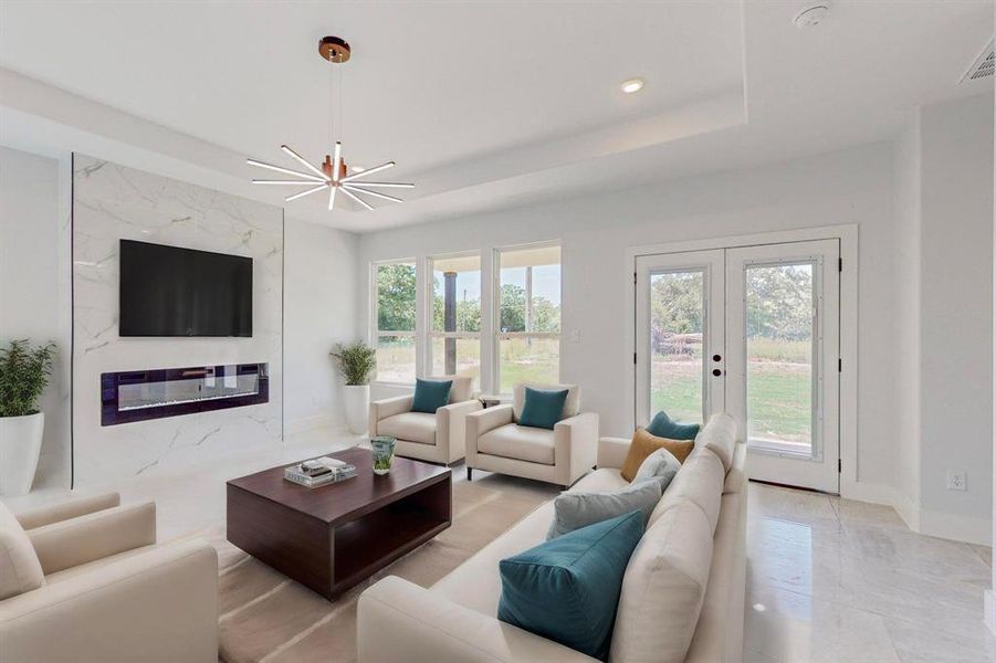 Staged Living room with french doors, a raised ceiling, a notable chandelier, and light tile patterned floors