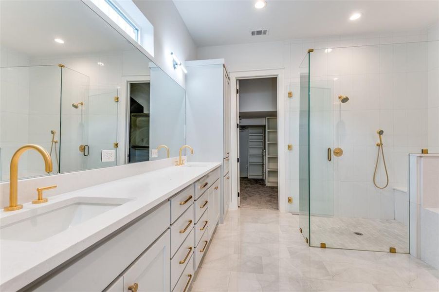 Bathroom featuring tile floors, dual sinks, a shower with door, and large vanity