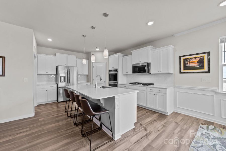 Modern, updated kitchen includes double wall oven, convection microwave, dishwasher, gas range, walk in pantry, expansive island and just off full sized laundry room with entry to garage.