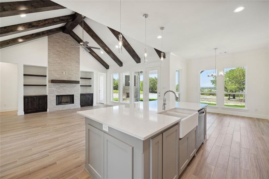 Kitchen with a kitchen island with sink, gray cabinetry, plenty of natural light, and decorative light fixtures