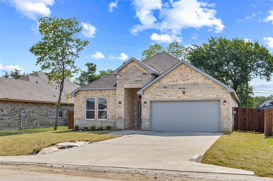 View of front facade featuring a garage and a front lawn