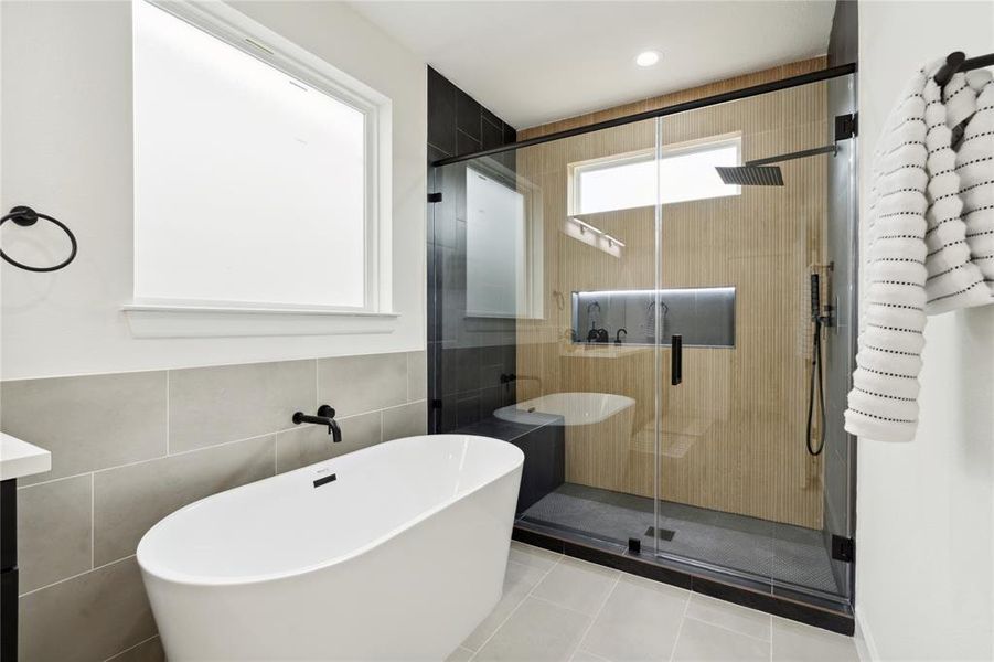Discover a beautifully designed frameless walk-in shower with sleek, modern fixtures, alongside a standalone tub for ultimate relaxation. This spacious retreat offers the perfect blend of elegance and comfort, ensuring a luxurious bathing experience.