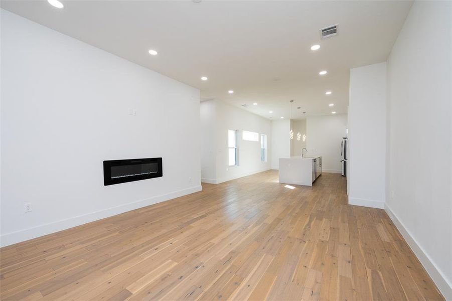 Unfurnished living room with sink and light hardwood / wood-style floors