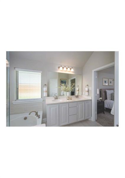 Bathroom featuring vanity, a bath, and lofted ceiling