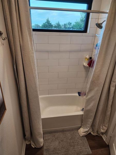 Bathroom with wood-type flooring, shower / bath combo, and a wealth of natural light