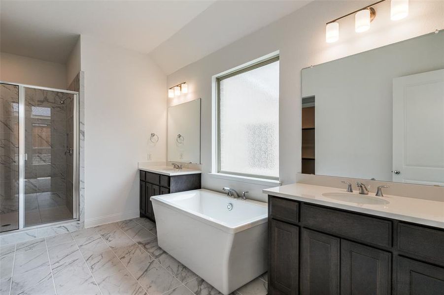 Bathroom featuring tile flooring, shower with separate bathtub, and double sink vanity