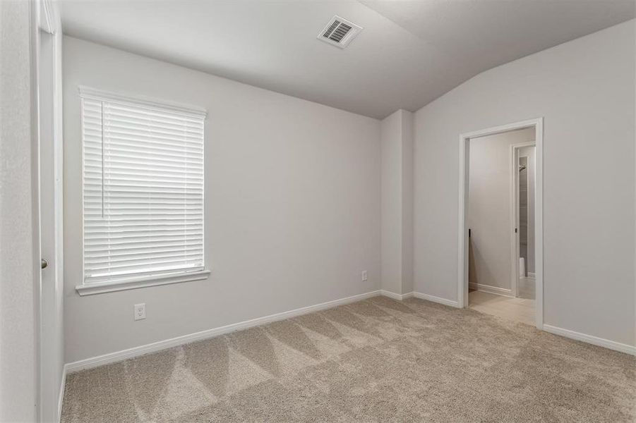 This additional bedroom provides a serene and private space, complete with plush carpeting and ample natural light from two large windows. The attached bathroom offers convenience and functionality, making it a perfect guest or children's room. Photos are from another Rylan floor plan.