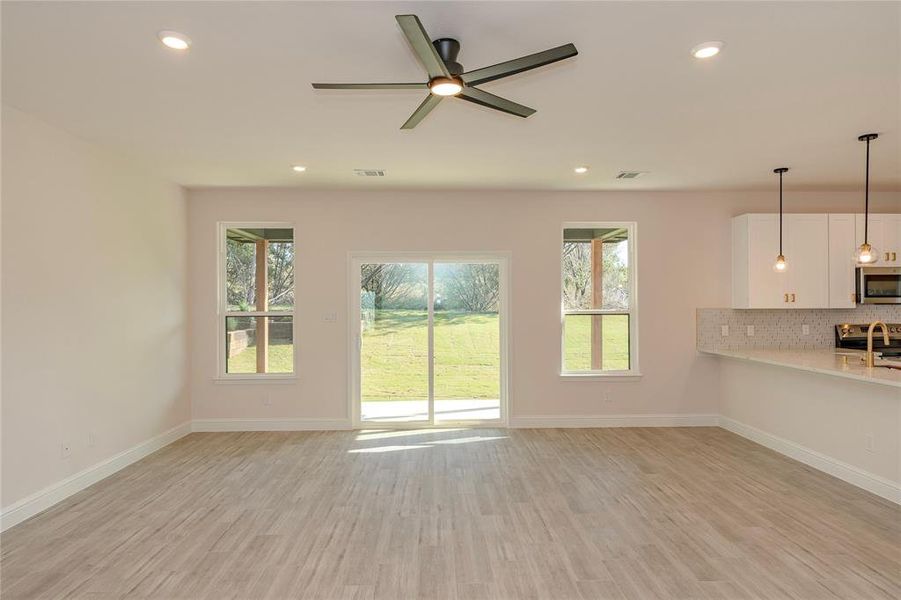 Unfurnished living room with light hardwood / wood-style flooring, ceiling fan, and plenty of natural light