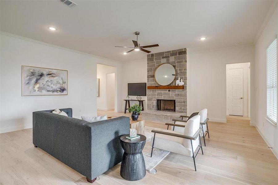 Living room featuring a stone fireplace, light hardwood / wood-style floors, ceiling fan, 10 ft ceilings and 8 ft doors