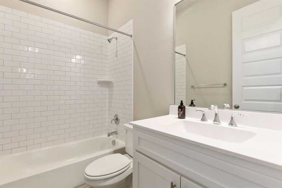 Full bathroom with vanity, tiled shower / bath combo, and toilet