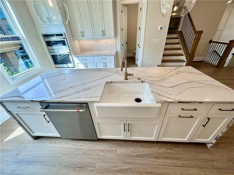 Porcelain white farmhouse sink paired with champagne, bronze, plumbing fixtures