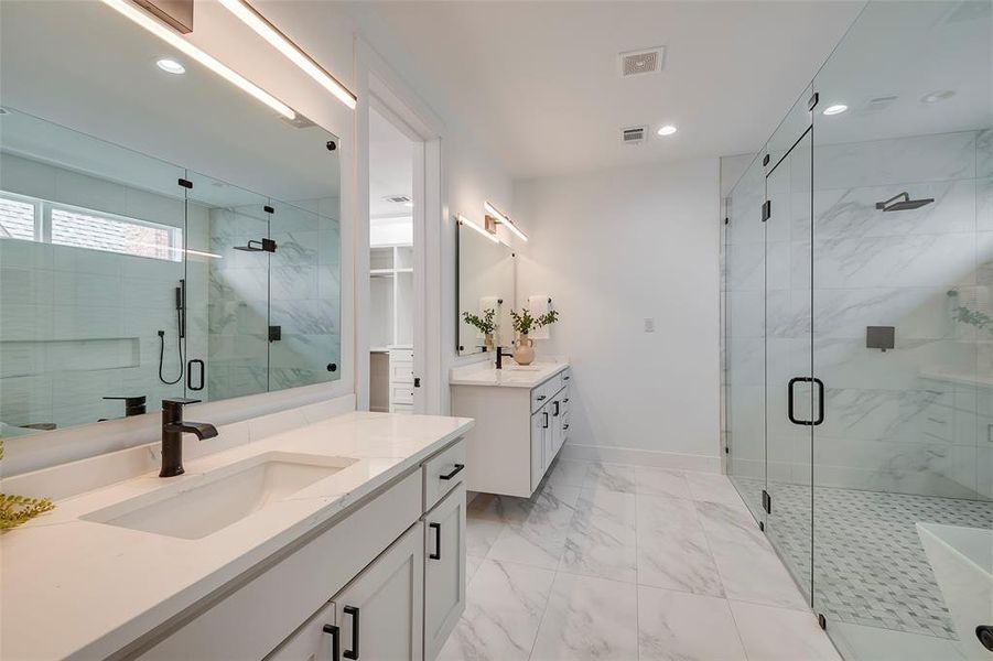 Bathroom featuring a shower with shower door, dual bowl vanity, and tile floors