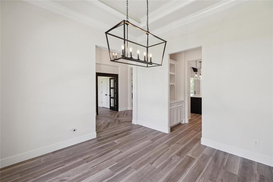 Unfurnished dining area with a tray ceiling, hardwood / wood-style floors, and an inviting chandelier