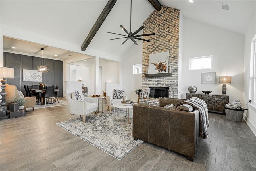 Living room with ceiling fan, beamed ceiling, a brick fireplace, high vaulted ceiling, and hardwood / wood-style floors