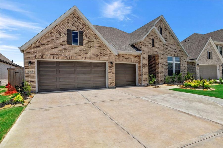 Charming Left View - Showcases the 3-car garage and extended driveway for easy access, highlighting the home's stunning brick design and inviting presence.