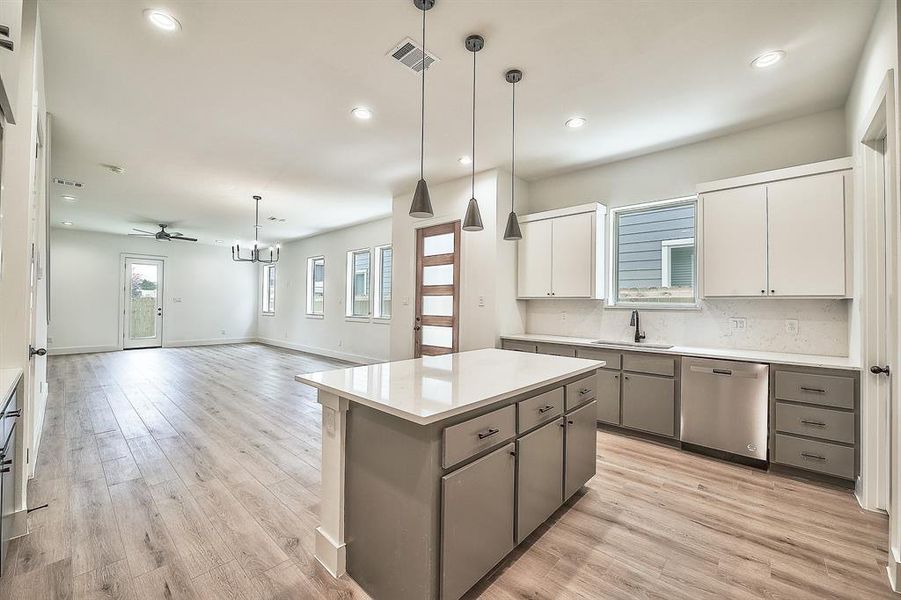 Kitchen with dishwasher, white cabinetry, gray cabinetry, and hanging light fixtures