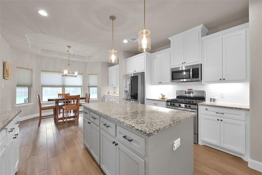 Large kitchen has custom island, cabinetry with under mount lighting, gas stainless appliances, overlooks living area and huge backyard