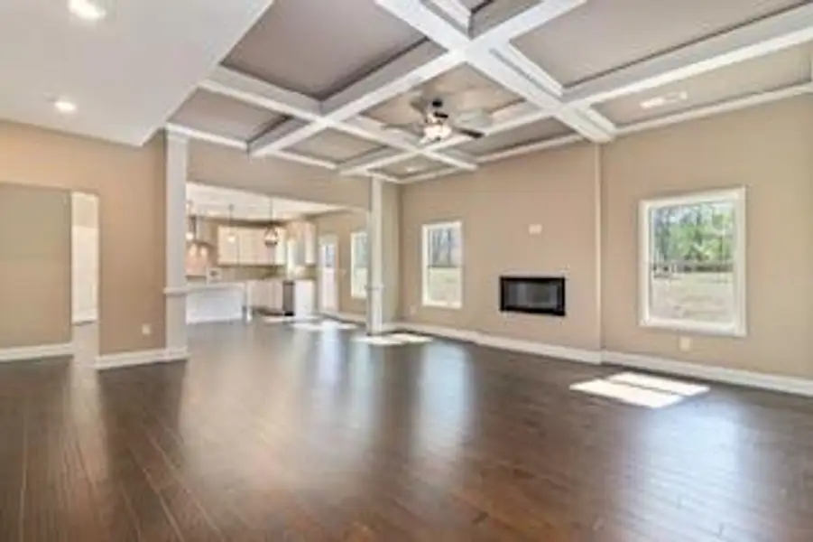 Unfurnished living room featuring ceiling fan, coffered ceiling, and dark hardwood / wood-style flooring