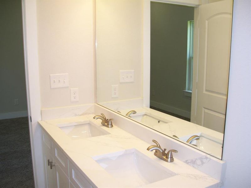 Ensuite bathroom featuring double sink vanity with quartz countertop