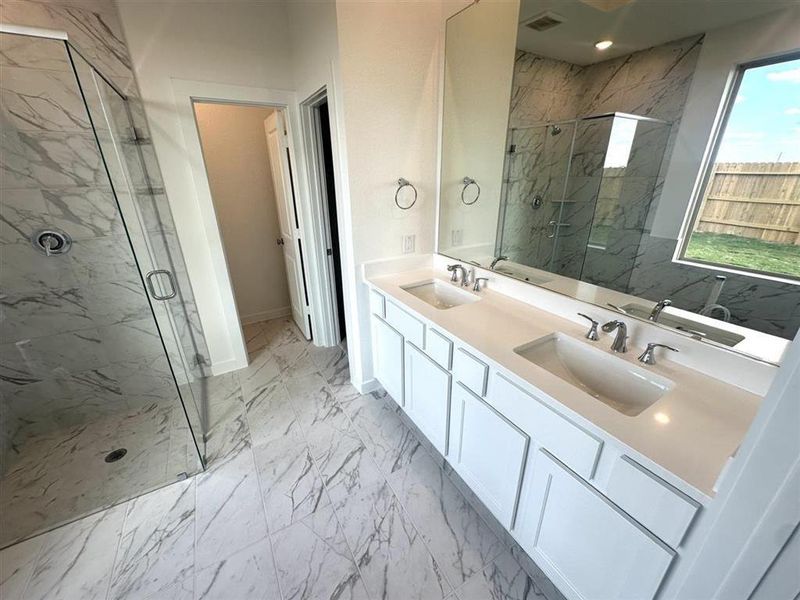 Primary bath with double sinks, upgraded tile flooring.