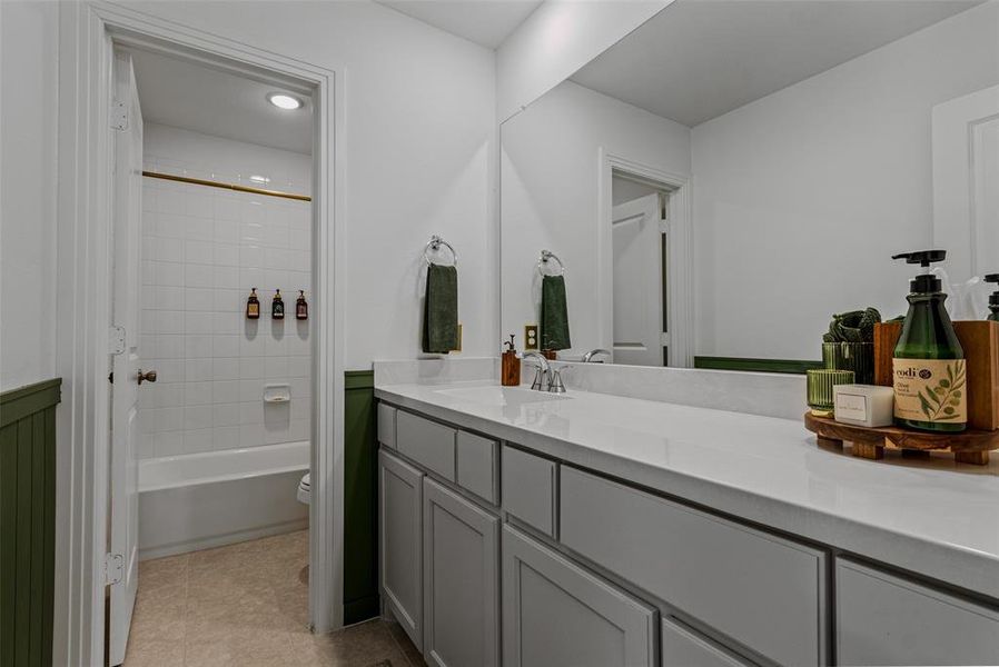 Full bathroom with vanity, tiled shower / bath combo, toilet, and tile patterned flooring