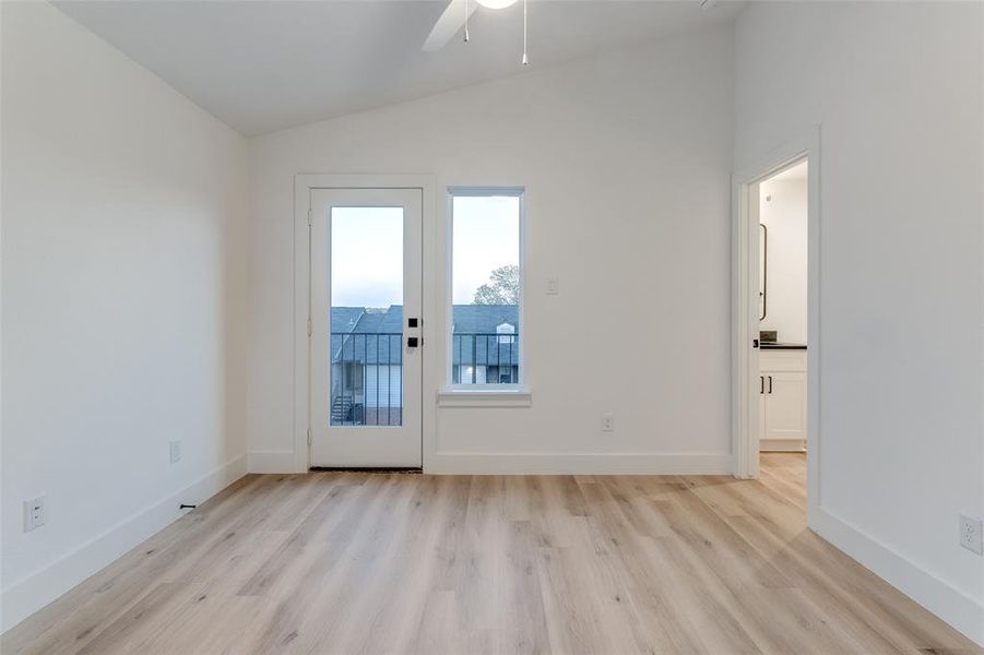 Empty room featuring light wood-type flooring, lofted ceiling, and ceiling fan