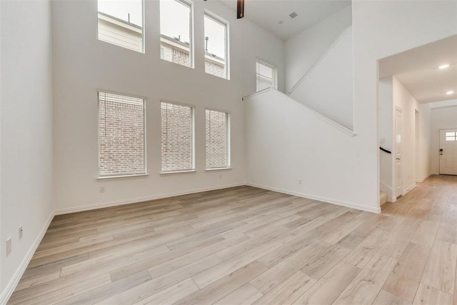 Unfurnished living room featuring a towering ceiling and light hardwood / wood-style flooring