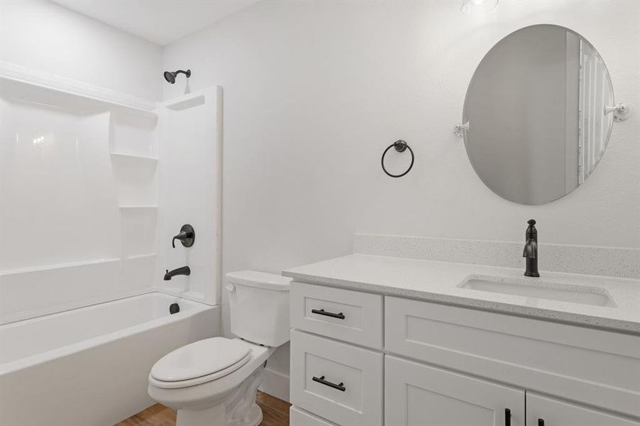 Full bathroom featuring hardwood / wood-style floors, shower / tub combination, vanity, and toilet