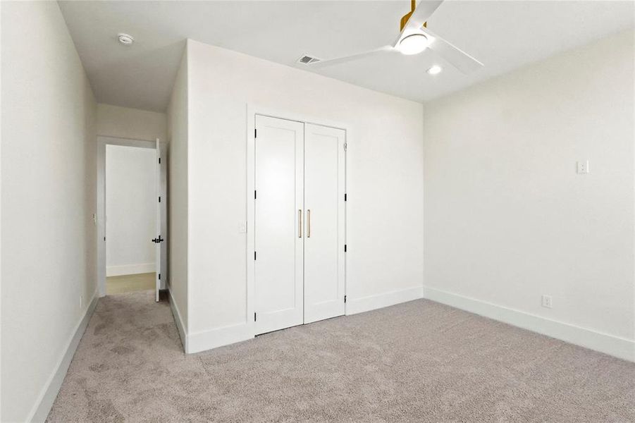 Unfurnished bedroom featuring a closet, light colored carpet, and ceiling fan