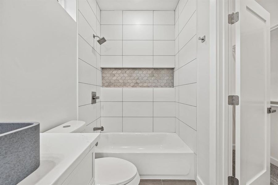 Full bathroom with vanity, tiled shower / bath combo, toilet, and tile patterned floors