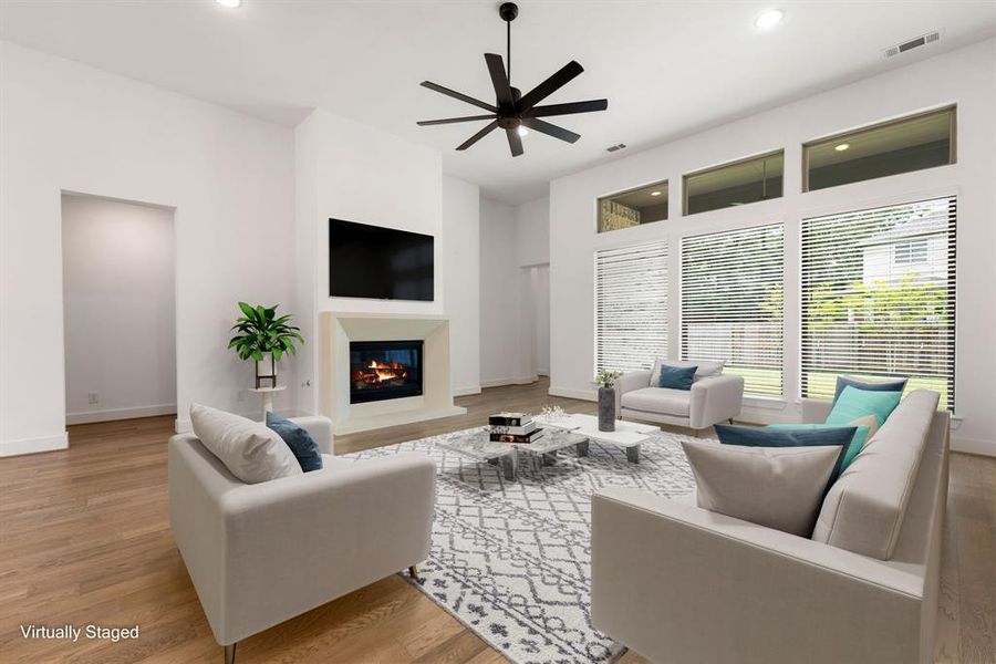 Gather the family and guests together in your lovely living room! Featuring soaring high ceilings, recessed lighting, modern ceiling fan, neutral paint, rich hardwood floors and a wall of windows that provide plenty of natural lighting throughout the day.