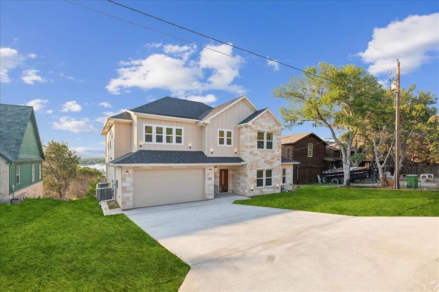 View of front of home featuring central air condition unit, a garage, and a front yard