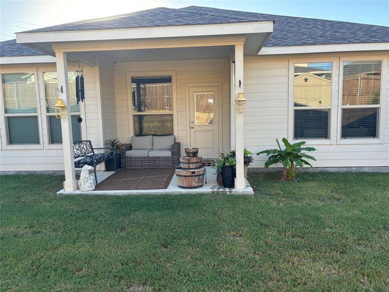 Entrance to property featuring an outdoor hangout area and a lawn