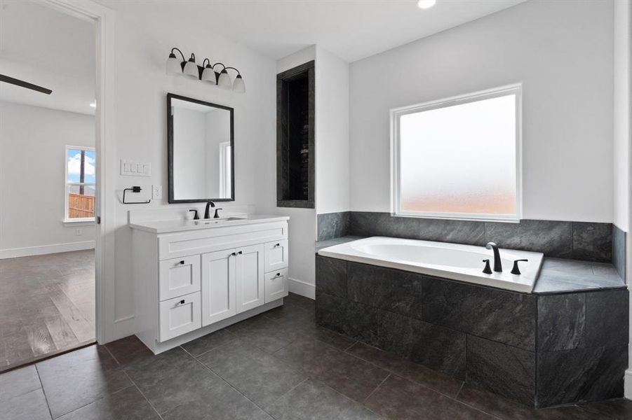 Bathroom featuring tiled tub, vanity, and hardwood / wood-style floors